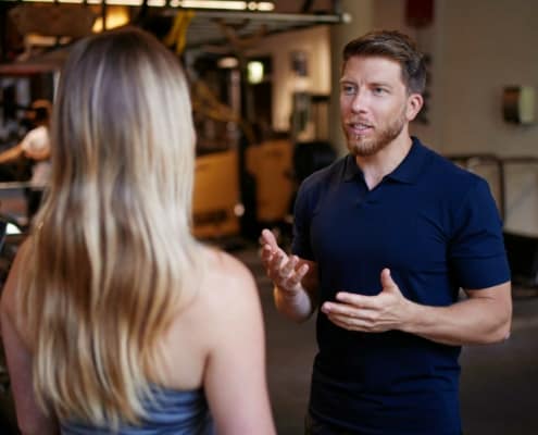 Ein Fitnesstrainer redet mit einer Frau in einem Fitnessstudio.