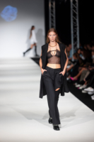 Ein Model in einem schwarzen Outfit und einem schwarzen BH geht einen Laufsteg auf der Vienna Fashion Week entlang